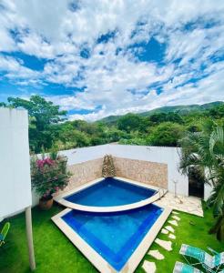 een achtertuin met een blauw zwembad en een grasveld bij Hotel Garden Suites Tonalá in Tonalá