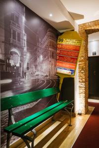 a green bench sitting next to a wall with a mural at Apart Hotel Torino in Turin