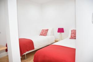 two beds in a room with white and red sheets at Cool Tailor Made 2 Bedroom Apartment in Lisbon