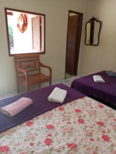 two beds in a room with a chair and a window at Villa Pareto Guest House in Macaé