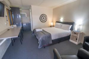 バーマグイにあるBermagui Motor Innのベッド、デスク、椅子が備わるホテルルームです。