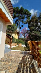 a stone walkway next to a house with trees at Mouton Blanc Campos do Jordão in Campos do Jordão