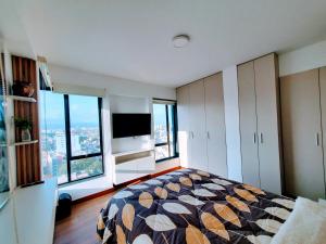 a bedroom with a bed and a tv and windows at Apartamento Frente a Parque en Urb. California in Víctor Larco Herrera