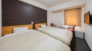 zwei Betten in einem Hotelzimmer mit Fenster in der Unterkunft Hotel Obihiro Hills in Obihiro