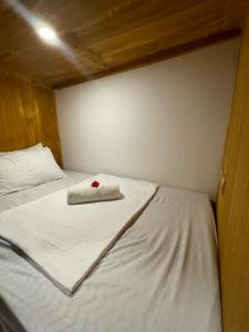 un letto bianco con un asciugamano sopra di Moon Bar Hostel a Port Barton