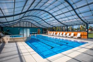 a large swimming pool with chairs and a glass ceiling at Tasman Holiday Parks - Merimbula in Merimbula