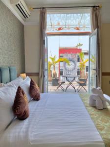 Cama blanca grande en habitación con balcón en Amarelo Hotel Solo en Solo