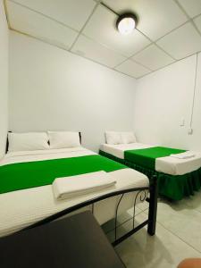 twee bedden in een kamer met groen en wit bij Hostal Pochote in León
