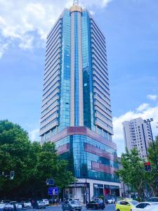um edifício de vidro alto com carros à frente em Lemon Hotel - Metro Line 1 Line 7 Changshu Road 200 meters em Xangai