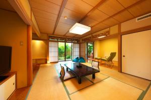 - un salon avec une table, des chaises et une télévision dans l'établissement Kagetsutei, à Shimoda
