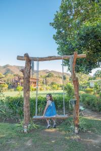a little girl sitting on a swing in a tree at The Nest House in Pai