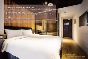 a bedroom with a large white bed and a bathroom at Calligraphy Greenway Hotel in Taichung