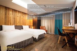 a hotel room with two beds and a desk at Calligraphy Greenway Hotel in Taichung