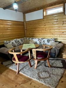 ein Wohnzimmer mit einem Sofa, einem Tisch und Stühlen in der Unterkunft Golden Wood House in Žabljak