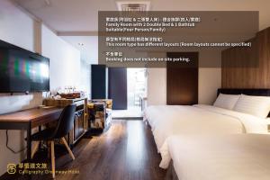a hotel room with two beds and a desk and a television at Calligraphy Greenway Hotel in Taichung
