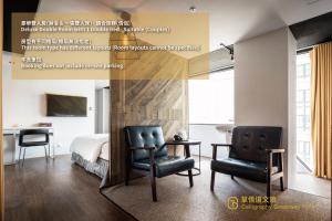 1 dormitorio con 2 sillas, 1 cama y escritorio en Calligraphy Greenway Hotel, en Taichung