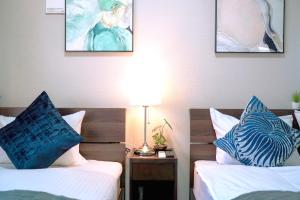 2 Betten mit blauen Kissen in einem Hotelzimmer in der Unterkunft Kuromon Royal Niponbashi in Osaka