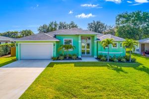 una casa verde con garaje en Sea La Vie Beach House, en Bonita Springs