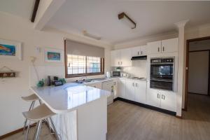 a kitchen with white cabinets and a counter top at 29A Ballina Crescent Port Macquarie in Port Macquarie +8 photos