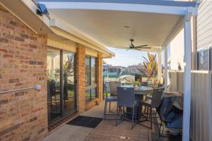 a patio with a table and chairs and a ceiling fan at 29A Ballina Crescent Port Macquarie in Port Macquarie