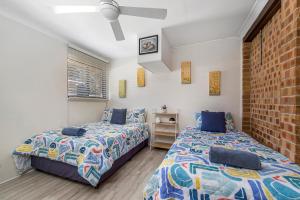 a bedroom with two beds and a brick wall at 29A Ballina Crescent Port Macquarie in Port Macquarie