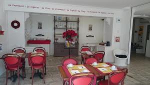 a dining room with red chairs and tables and a kitchen at Hotel Le 5 in Martigues