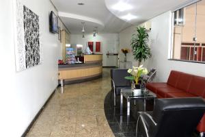 una sala de espera con sofás, mesas y un mostrador en Domus Hotel Veneza Ipatinga, en Ipatinga