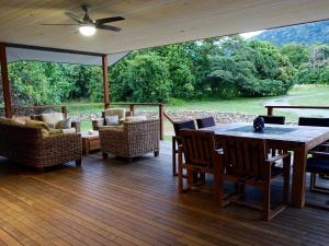 a screened porch with a table and chairs and a couch at Coconut Beach House in Cape Tribulation