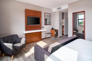um quarto de hotel com uma cama, um sofá e uma televisão em Protea Hotel by Marriott Pretoria Hatfield em Pretoria