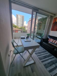 una mesa y una silla en una habitación con una ventana grande en Hermoso departamento a pasos de UdeC en Concepción