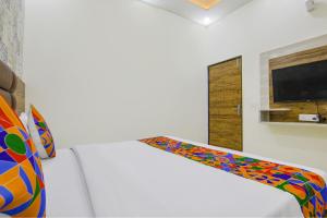 een slaapkamer met een wit bed en een kleurrijke deken bij Hotel RD in Zirakpur
