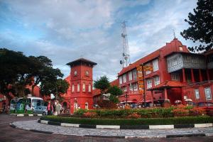 a red building with a clock tower on a street at Al Huda Hotel in Malacca