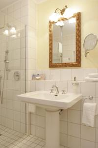 a white bathroom with a sink and a mirror at Hotel Landhaus Milser in Duisburg