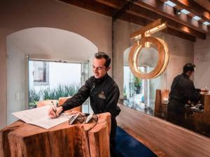 サンミゲル・デ・アジェンデにあるLuxury 2BR Condo AC Near Rosewood - 3 min walkのカウンターに座って書類に署名している男性