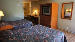 a hotel room with two beds and a television at Executive Inn & Suites in Orange