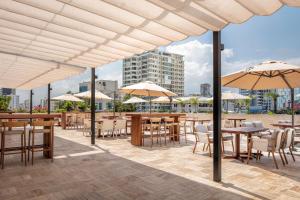 un patio avec des tables, des chaises et des parasols dans l'établissement Santo Domingo Marriott Hotel Piantini, à Saint-Domingue