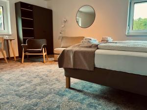 a bedroom with a bed and a chair and a mirror at Pension Auer in Liebenfels