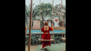 a girl in a red dress sitting on a swing at Tropical Homestay Phu Yen in Tuy Hoa