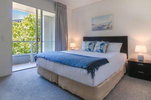 a bedroom with a large bed and a large window at 325 Harbour Lights with Garden View in Cairns