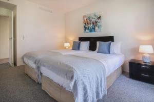 um quarto com uma grande cama branca com almofadas azuis em 325 Harbour Lights with Garden View em Cairns