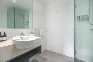 a white bathroom with a sink and a shower at 325 Harbour Lights with Garden View in Cairns
