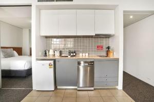 a kitchen with a sink and a refrigerator and a bed at 903 Harbour Lights with Ocean Views in Cairns