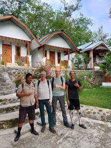 a group of men standing in front of a house at Asim Paris Guesthouse in Bukit Lawang