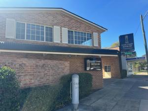 a brick building with a sign in front of it at Clock Tower Motor Inn in Coonabarabran