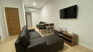 idyllic apartment في شاطئ تشاوينغ: غرفة معيشة مع أريكة سوداء وطاولة