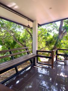 een bankje op het balkon van een huis met bomen bij Jungle Vibes in Thongsala