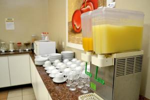 a kitchen counter with cups and plates and a juicer at Domus Hotel Veneza - Ipatinga in Ipatinga