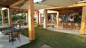 a patio with tables and a bar with people in the background at Olympion Sunset Halkidiki in Fourka
