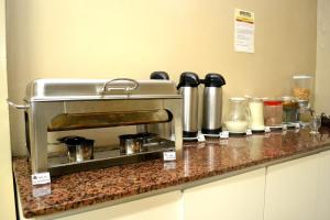 a kitchen counter with a coffee maker and other appliances at Domus Hotel Veneza - Ipatinga in Ipatinga