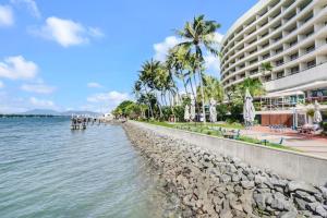 a beach next to a large building with palm trees at 602 Harbour Lights with Ocean Views in Cairns